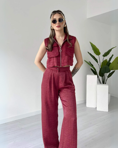 Woman wearing a stylish sleeveless maroon co-ord set with zip-up crop top and high-waisted wide-leg pants – minimal indoor fashion shoot