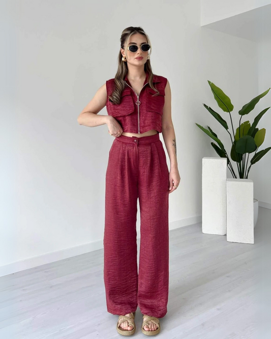 Woman wearing a stylish sleeveless maroon co-ord set with zip-up crop top and high-waisted wide-leg pants – minimal indoor fashion shoot